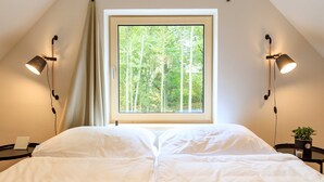 A bedroom with a large window, two bedside lamps, a bedside table with a plant, and a bed with white bedding. - Villa in Cervene Janovice Near Kutna Hora Castle (Červené Janovice)