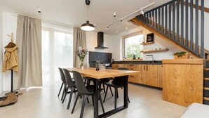 A modern kitchen with a wooden island, black chairs, and a dining table. - Villa in Cervene Janovice Near Kutna Hora Castle (Červené Janovice)