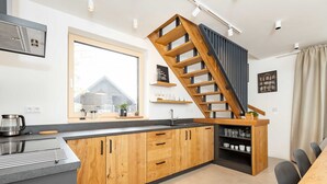 A modern kitchen with wooden cabinets, a built-in stove, and a wooden staircase. - Villa in Cervene Janovice Near Kutna Hora Castle (Červené Janovice)