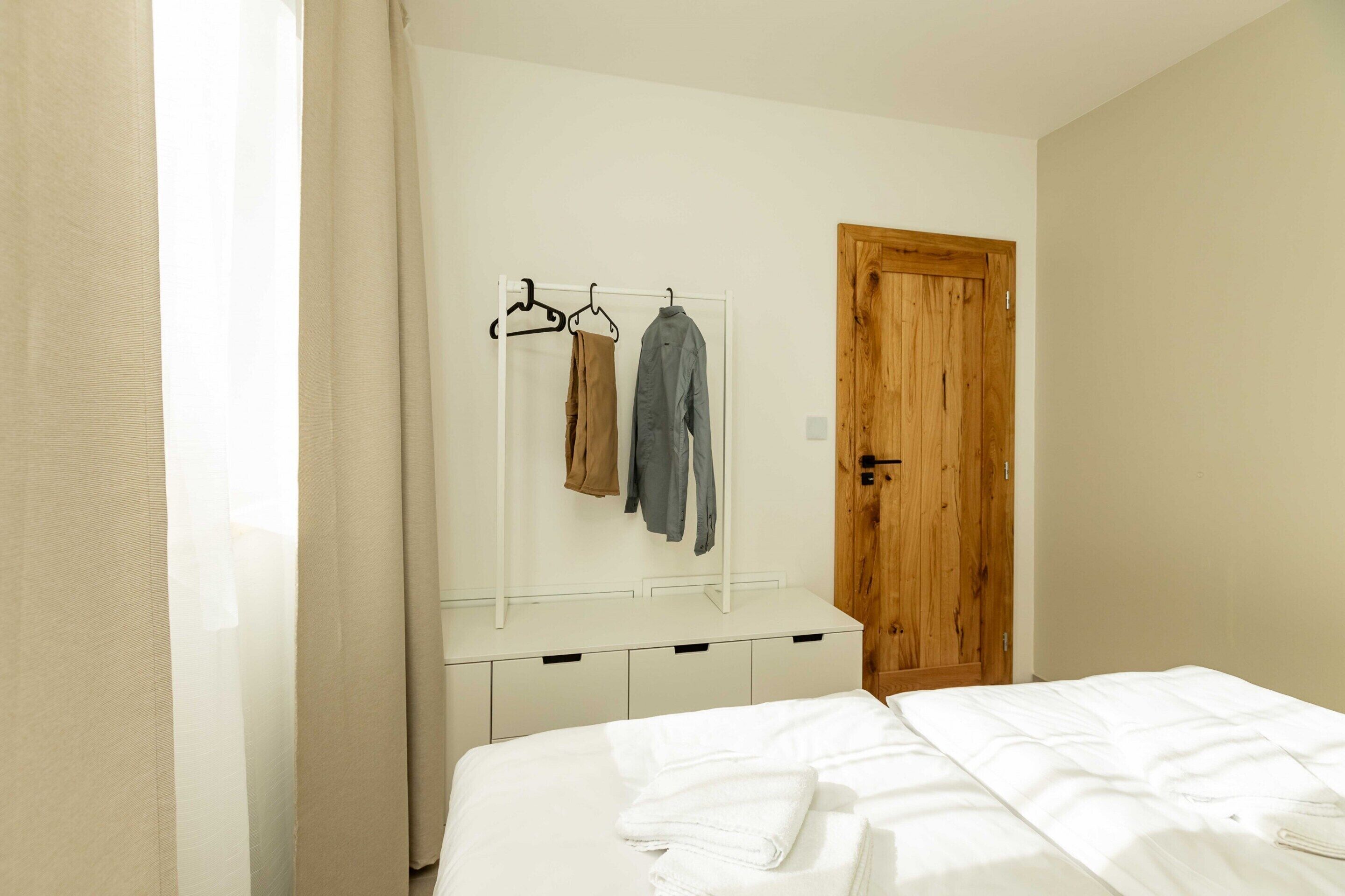 Ein Schlafzimmer mit einem Bett, einer Holztür und einem Kleiderständer mit zwei Kleiderbügeln.