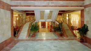 A grand lobby with a marble floor, a central staircase, and potted plants. - Olive Garden Hotel Baku (Baku)