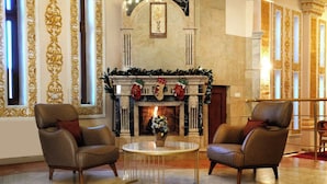 A luxurious lobby with a fireplace, two leather armchairs, and a round table. - Olive Garden Hotel Baku (Baku)
