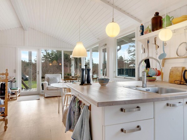 A modern kitchen with a large island, pendant lights, and a view of the outdoors. - 5 Star Holiday Home in Lokken (Lokken)