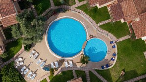 An aerial view of a resort with two large swimming pools, surrounded by lounge chairs and a well-maintained garden. - Ancora Sardinia Seaside Apartment (Badesi)