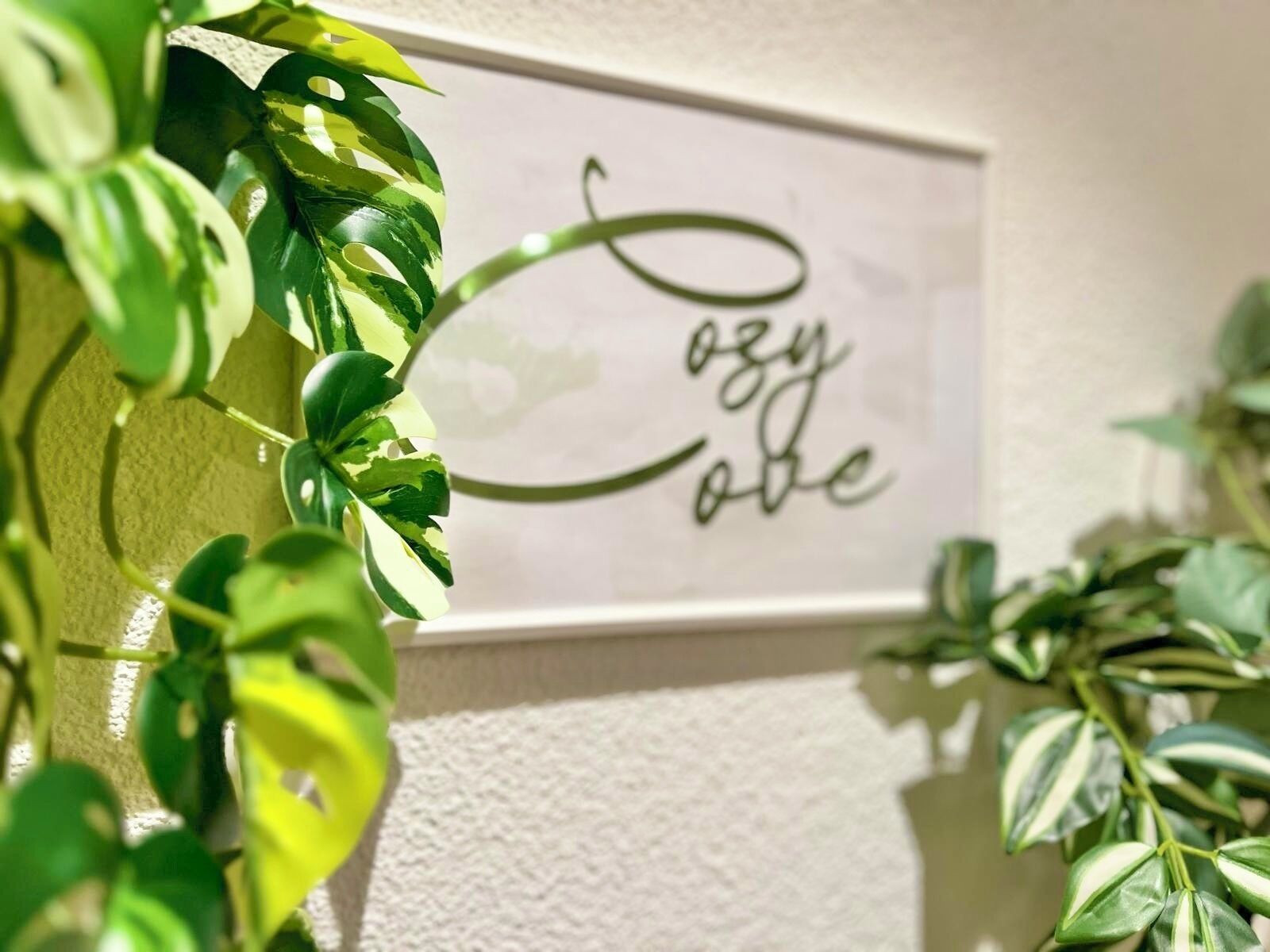 Une affiche encadrée avec l’inscription « amour facile » sur un mur à texture, entourée de plantes vertes.