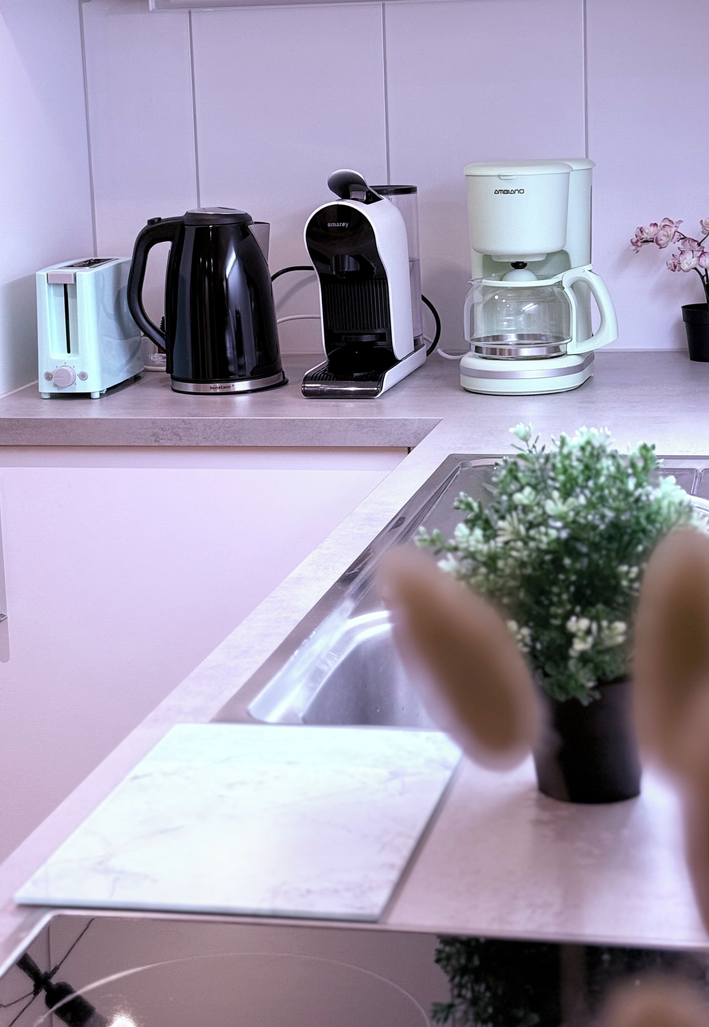 Une cuisine équipée d’une machine à café, d’un grille-pain et d’une bouilloire, le tout posé sur le plan de travail.