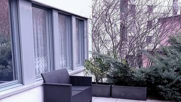 Eine moderne Außenpatio mit einem schwarzen Rattan-Sofa, einem kleinen Tisch und einem Blumentopf.
