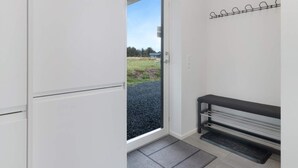 A modern room with a sliding glass door leading to a garden. - 5 Star Holiday Home in Lokken (Lokken)