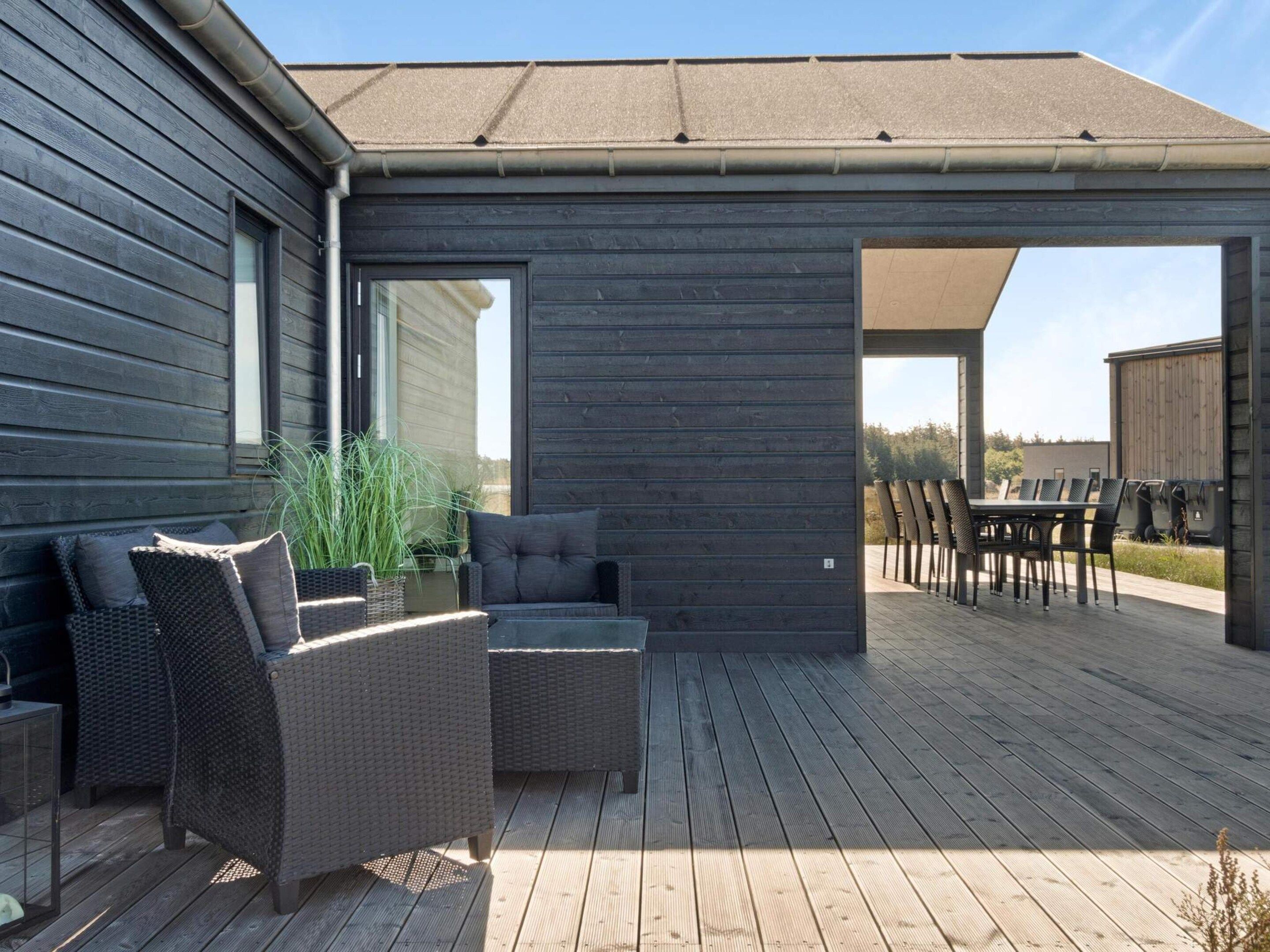 An outdoor patio with wicker furniture, a table, and chairs.