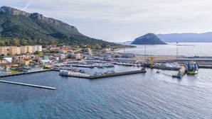 A coastal marina with boats docked, a bridge, and buildings in the background. - La Delfina by Interhome (Golfo Aranci)