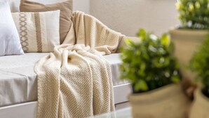 A cozy room with a sofa, pillows, and a blanket. - La Delfina by Interhome (Golfo Aranci)