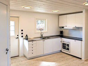 A modern kitchen with white cabinetry, a stainless steel sink, and a built-in oven. - 5 Star Holiday Home in Marstrand (Marstrand)