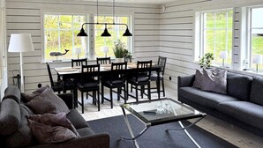 A modern living room with a sofa, a coffee table, and a dining area with chairs and a table. - 5 Star Holiday Home in Marstrand (Marstrand)