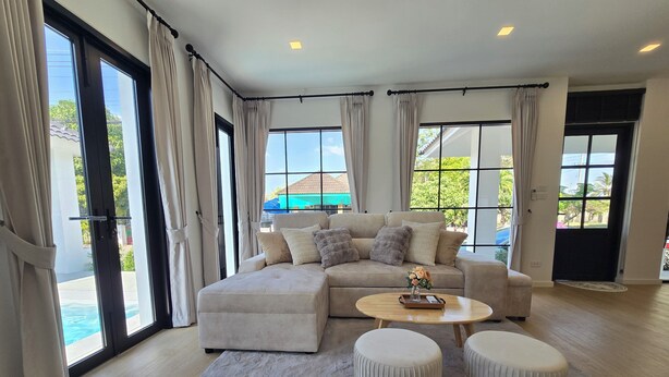 A spacious living room with a large sectional sofa, a round coffee table, and two ottomans.