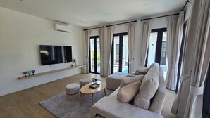 A modern living room with a large flat-screen TV, a sofa, a coffee table, and a rug.