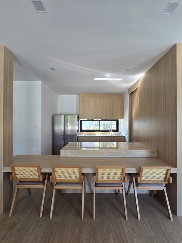 Una cocina moderna con armarios de madera, un refrigerador de acero inoxidable y una isla grande con asientos.