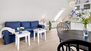 Un salon moderne avec un canapé bleu, une table basse blanche et une table à manger avec des chaises.