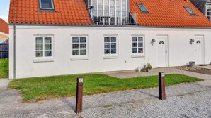 Un bâtiment à deux étages, doté d’un toit recouvert de tuiles rouges, de nombreuses fenêtres et d’un petit balcon.