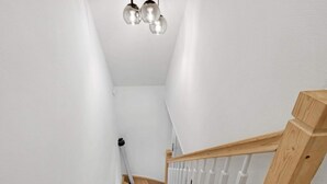 Un escalier en bois avec des rampes blanches et un luminaire au-dessus.