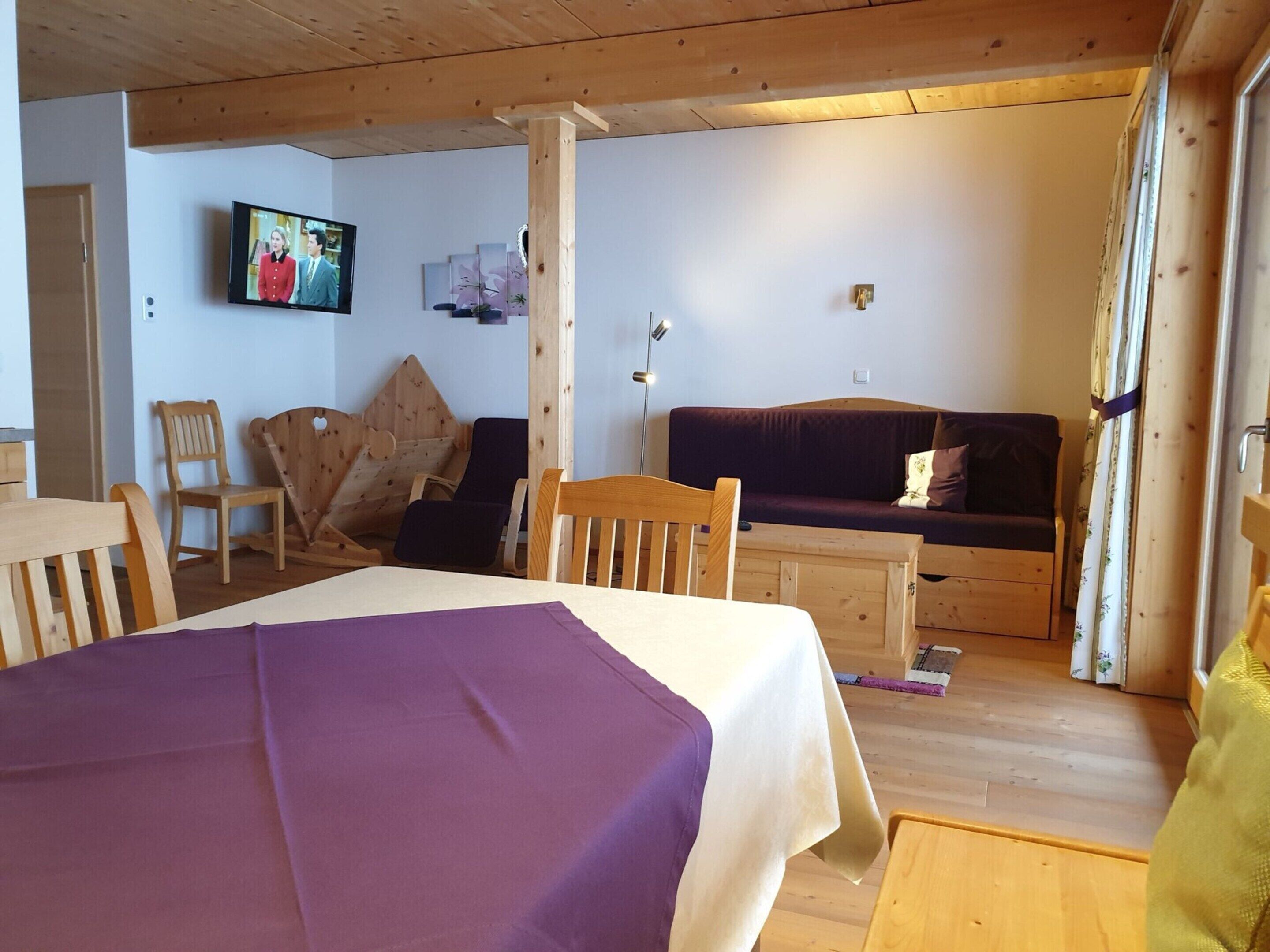 A cozy room with a bed, wooden furniture, a television, and a couch.