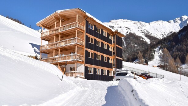 A multi-story wooden building with balconies, surrounded by snow-covered mountains. - Apartment in Kals Near Ski Slopes (Kals am Grossglockner)