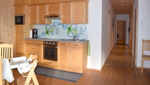 A kitchen with wooden cabinets, a microwave, a coffee maker, and a sink. - Apartment in Kals Near Ski Slopes (Kals am Grossglockner)