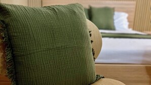 Un fauteuil vert recouvert de tissu, doté d’accoudoirs en bois et accompagné d’une table ronde en bois.