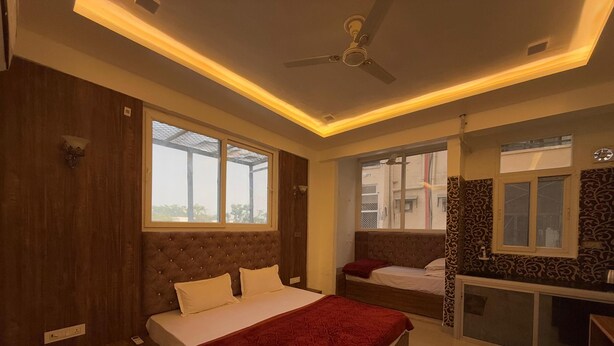 A bedroom with two beds, a ceiling fan, and a window. - Shree Radha Residency-near ISKCON Temple (Vrindavan)