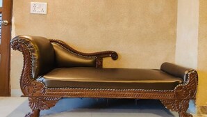 A brown leather sofa with ornate carvings against a beige wall. - Shree Radha Residency-near ISKCON Temple (Vrindavan)