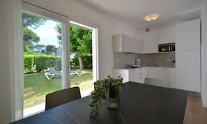 A modern kitchen with white cabinets, a black countertop, and a dining table with a potted plant. - Detached villa with beautiful garden (Bibione)