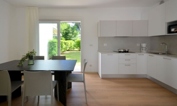 Una cocina moderna con armarios blancos, una mesa de comedor con sillas y vistas a la vegetación.
