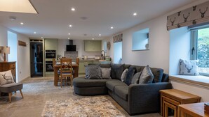 A modern living room with a sectional sofa, a dining area, and a kitchen. - Discover the charm of this wonderful barn, nestled in the Peak District. (Rushton Spencer)