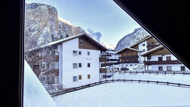 Ein schneebedecktes Dorf mit Gebäuden, auf denen "Tramont" steht.