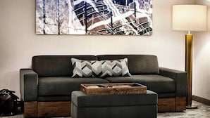 Ein modernes Wohnzimmer mit einer Couch, einem Hocker und einem Couchtisch aus Holz.
