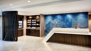 Ein moderner Empfangsbereich mit einer Rezeption, Bücherregalen und einer Wand mit Text.