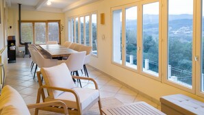 A spacious dining area with a long table and multiple chairs, large windows with a view of the countryside, and a cozy seating area with a bench and chairs. - "Sur Place" 4-12 people. Ideally suited for two or a large family. (Carcès)