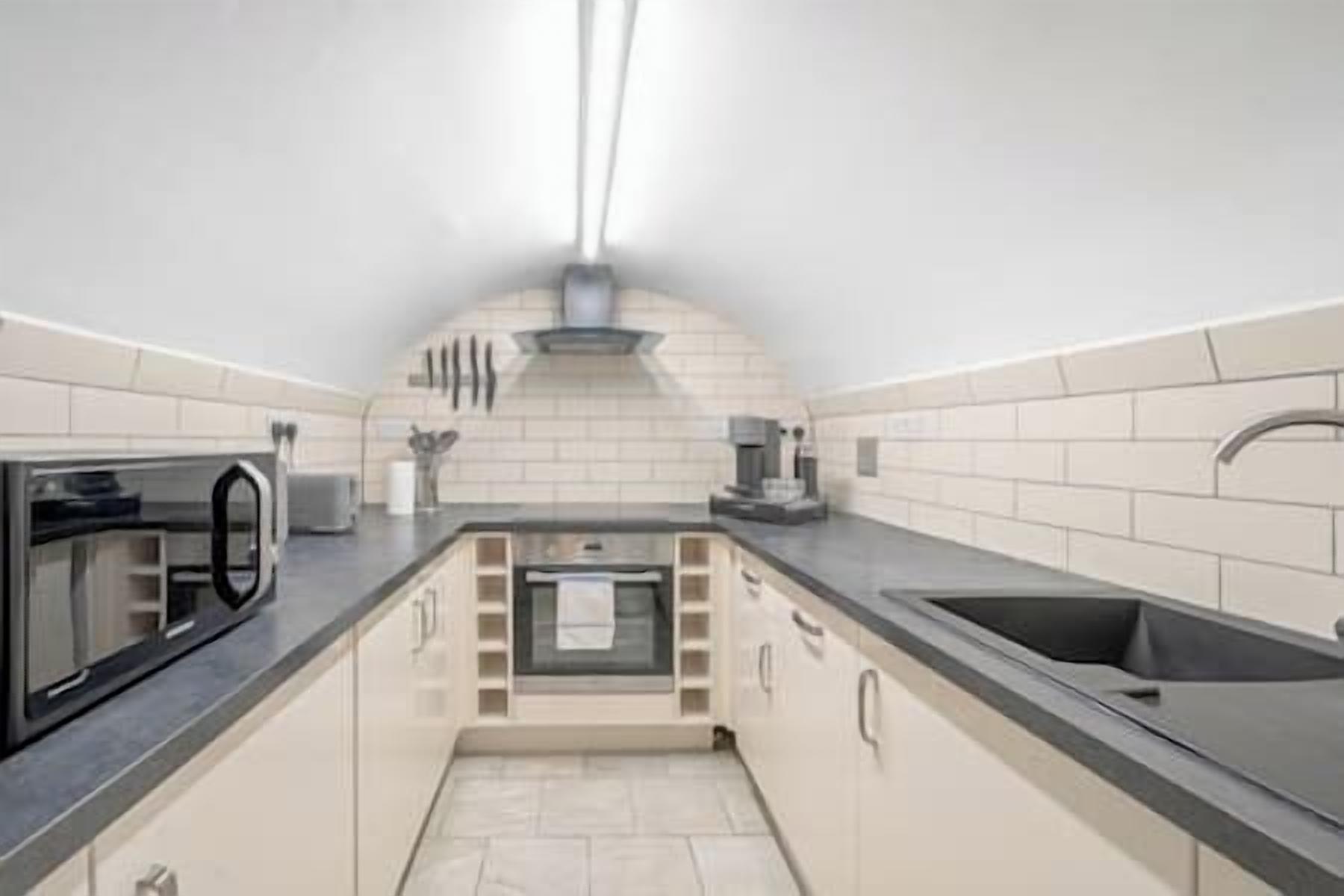 Una cocina compacta con horno integrado, un lavamanos y una campana extractora.