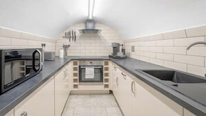 A compact kitchen with a built-in oven, a sink, and a range hood. - Marylebone / Baker Street 2Bed (Greater London)