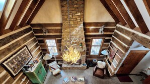 A log cabin interior with a stone fireplace, wooden beams, and a leather sofa. - Luxurious 2-bedroom cabin @ Canyon of the Ancients Guest Ranch in McElmo Canyon  (Cortez)