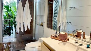 Une salle de bain moderne avec une douche en verre, des toilettes blanches et un meuble-lavabo doté d’un grand miroir.