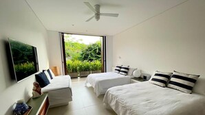Une chambre moderne avec deux lits simples, un ventilateur de plafond, une grande fenêtre donnant sur un paysage verdoyant et un téléviseur à écran plat fixé au mur.