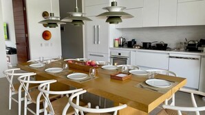Une cuisine moderne avec des meubles blancs, un îlot central en bois et des luminaires suspendus.
