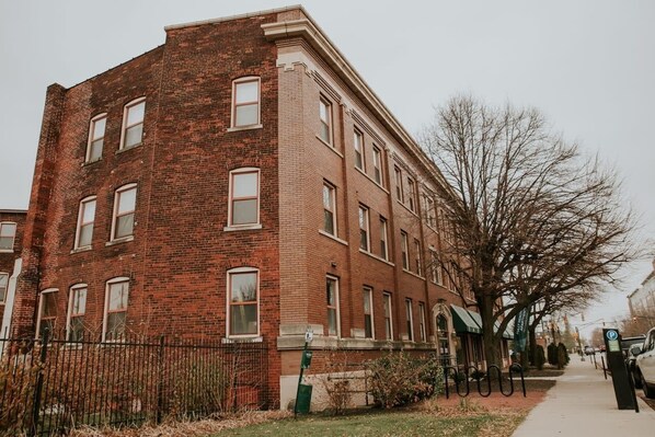 A red brick building with multiple windows and a sidewalk in front.