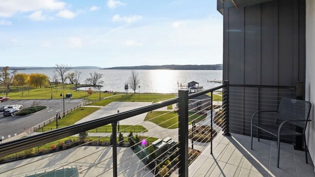 Ein Balkon mit Blick auf ein Gewässer, einen Parkplatz und eine Grünfläche.
