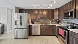 Eine moderne Küche mit Edelstahlgeräten, dunklen Holzschränken und einem hellen Holzboden.