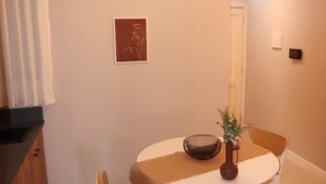 A dining area with a round table, two chairs, a vase with a plant, and a hanging light fixture. - Tranquil studio with AC in Rabat - Studio No.2  (Rabat)