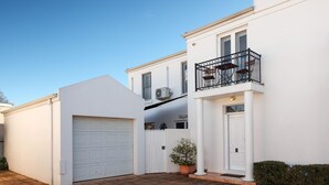 A two-story house with a white exterior, a garage, and a balcony with a black railing.