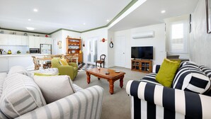 A living room with striped sofas, a wooden coffee table, and a television.