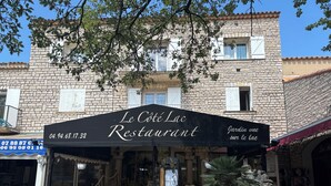 Un edificio de piedra con un letrero que dice 'Le Côté Lac Restaurant' y un jardín en la planta baja.