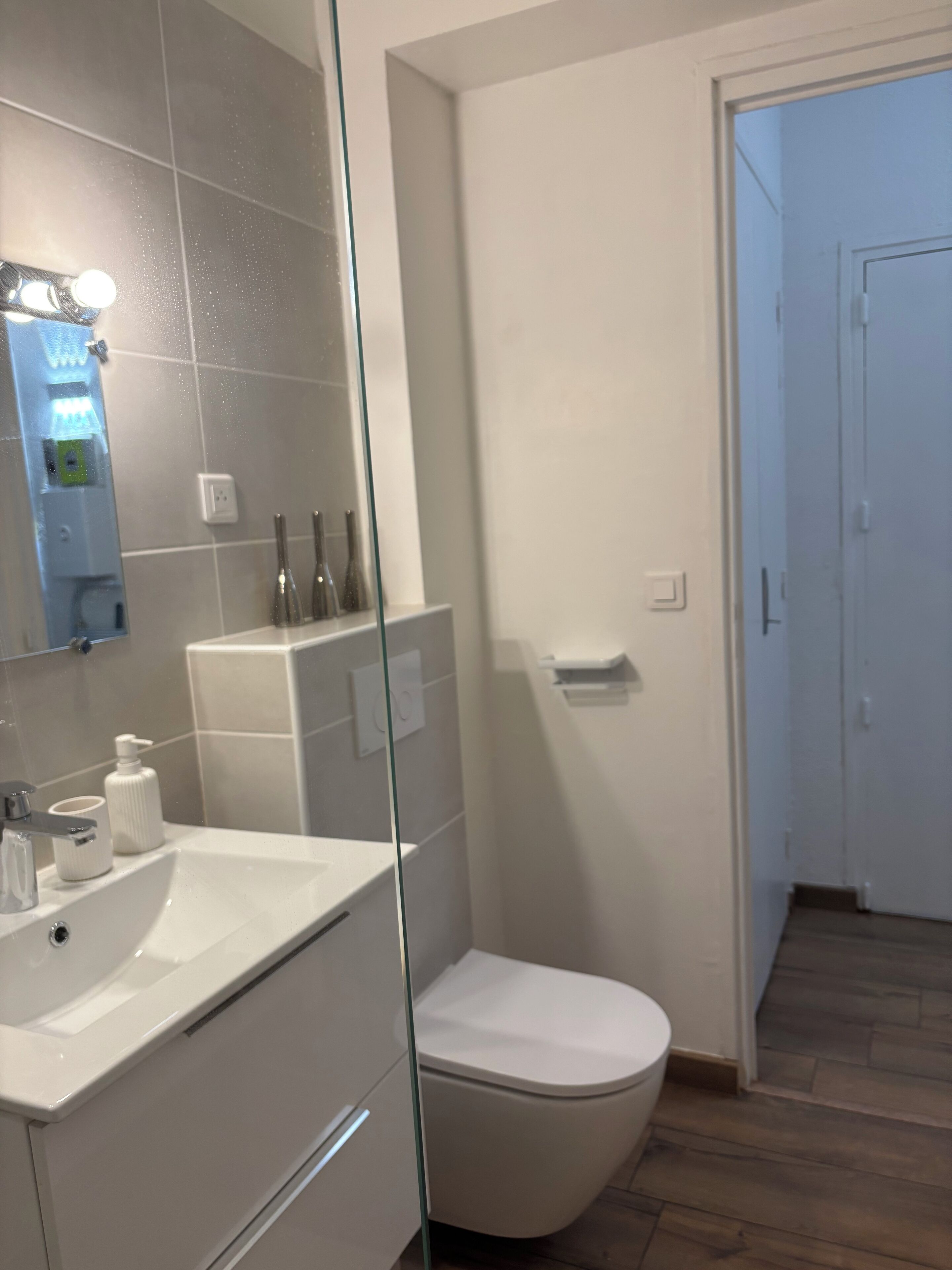 Een moderne badkamer met een wit wastafel, spiegel en toilet.